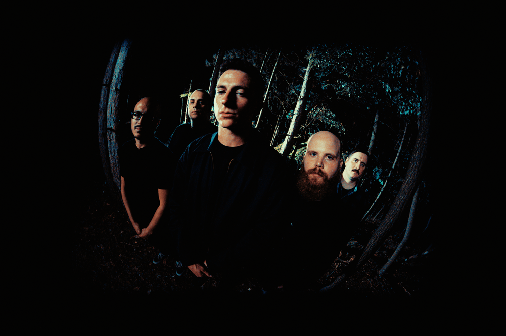 Dark fisheye lens photo of band standing in the woods facing the camera