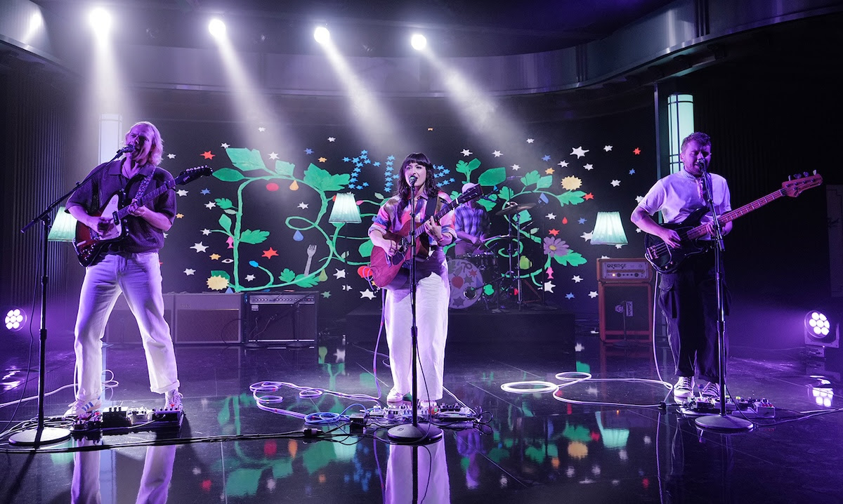 The Beths performing with purple lighting around them.