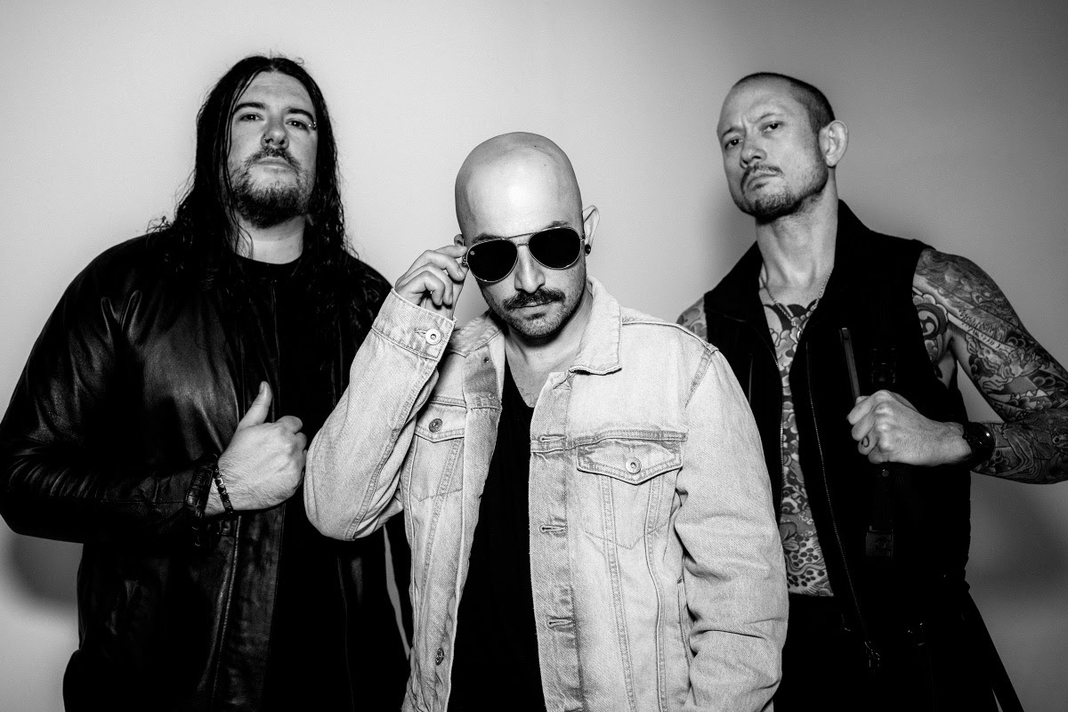 Members of Trivium stand in front of a white wall in a black and white photo.