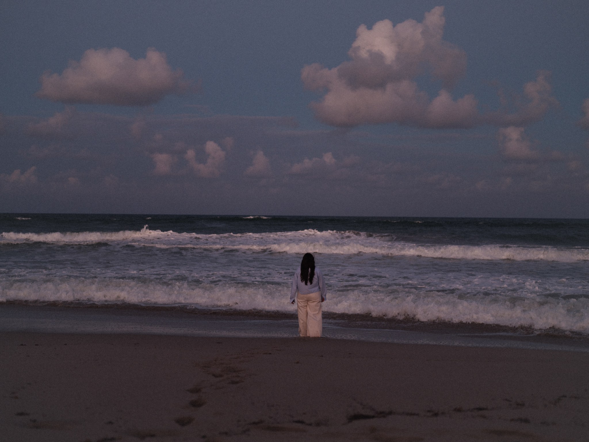 Gigi Perez walking toward the ocean.