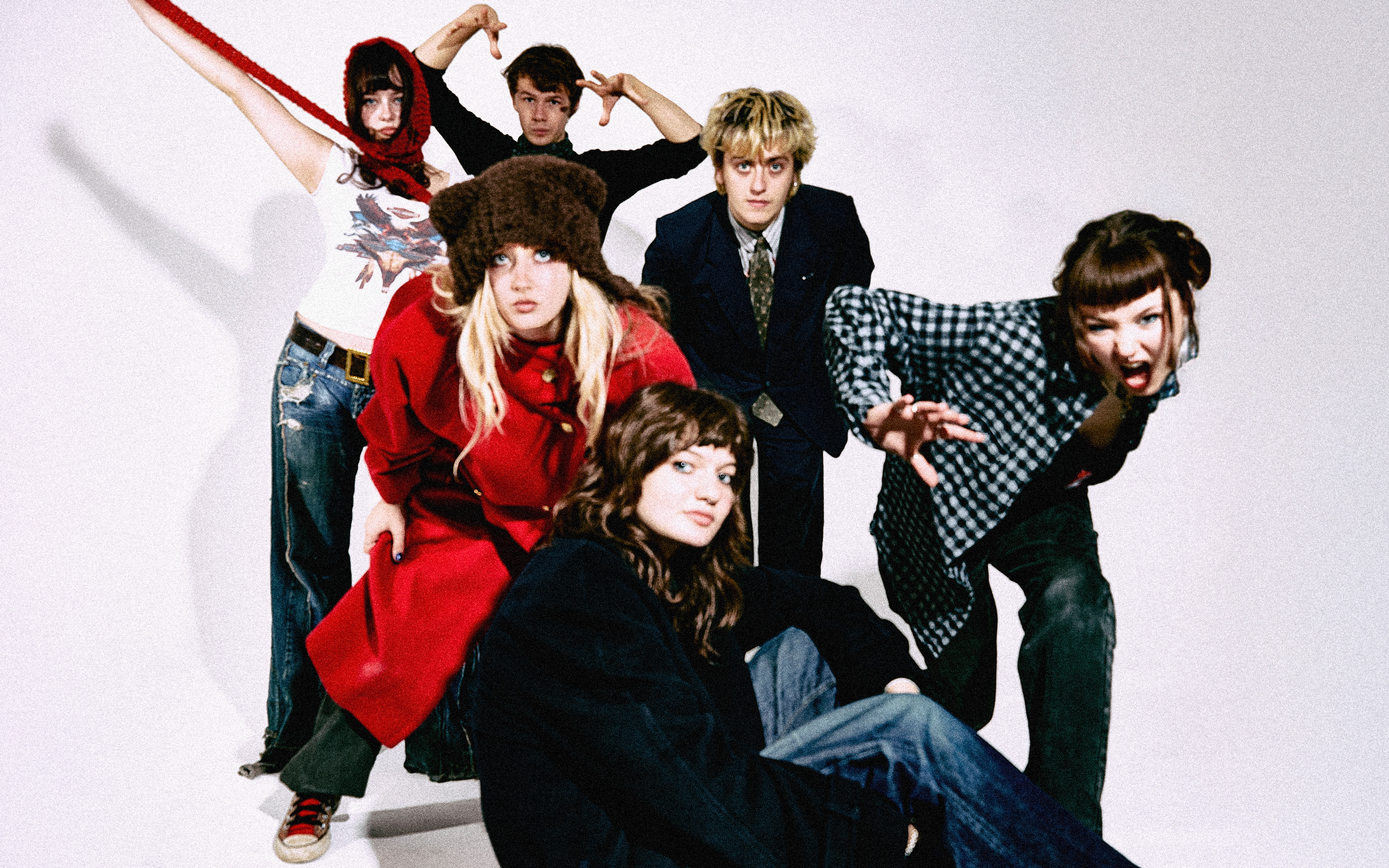 Members of Man/Woman/Chainsaw in front of a white background. Some are sitting some are standing.