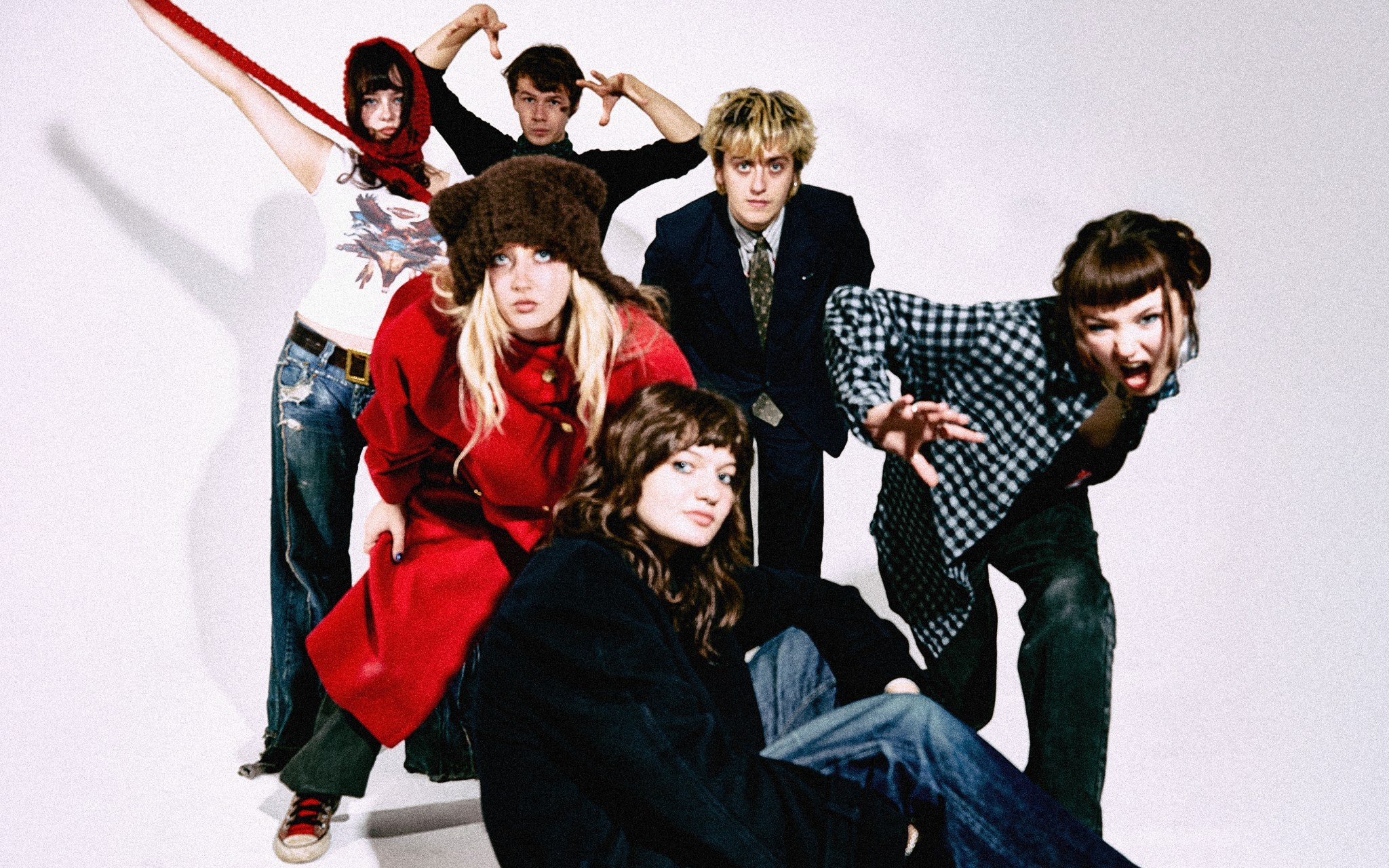 Members of Man/Woman/Chainsaw in front of a white background. Some are sitting some are standing.