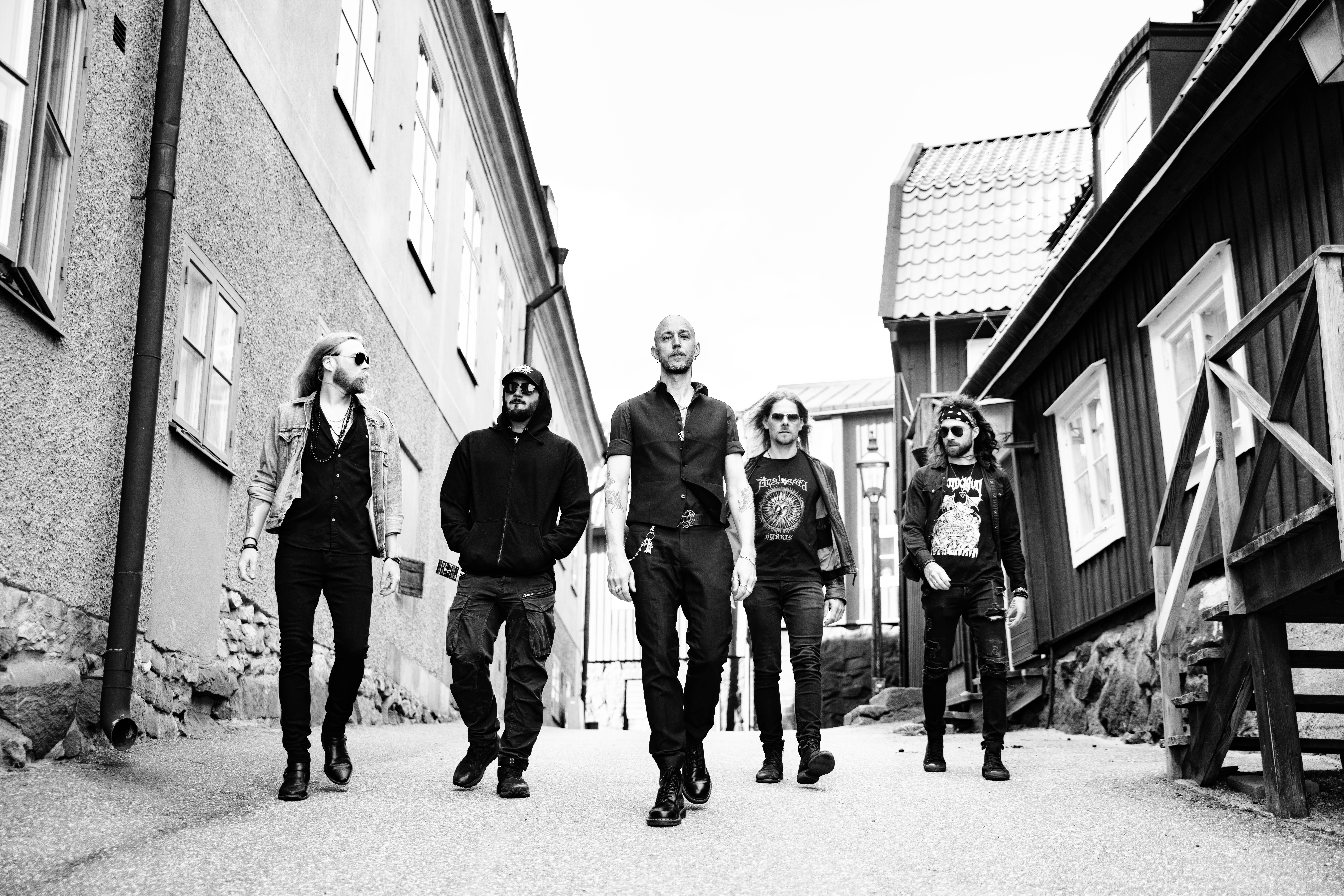 Band members walking forward in a horizontal line in a black and white outdoor photo.