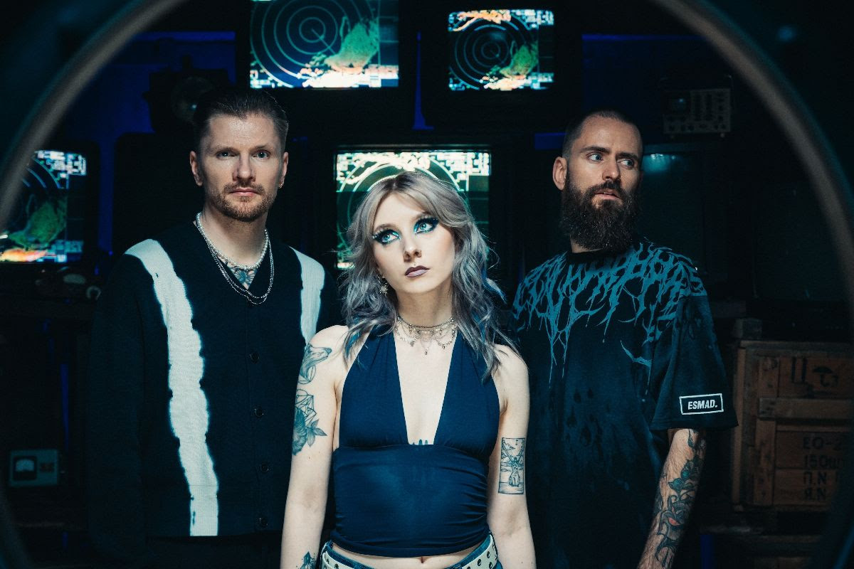 Members of Future Palace standing in front of submarine monitors in a dark room.