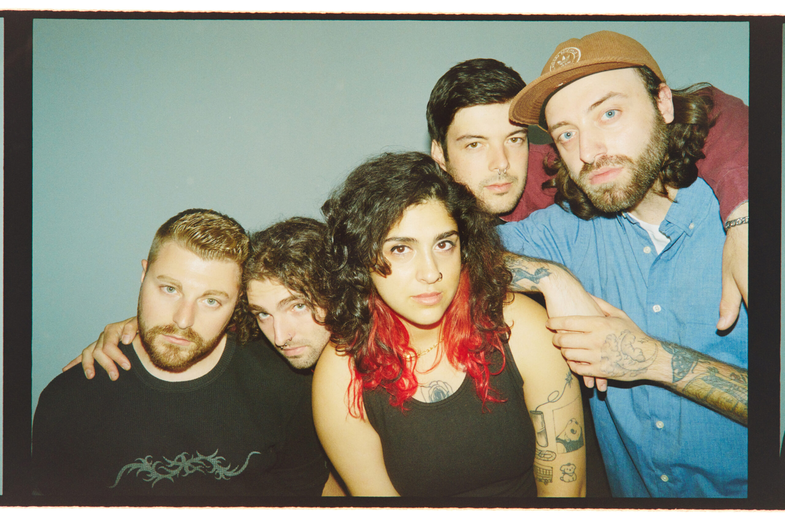 Sweet Pill Members huddled together in front of a teal wall.