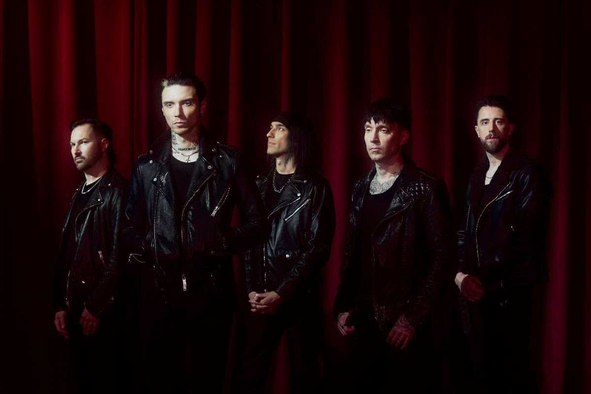 Black Veil Brides all wearing black standing in front of a red curtain.
