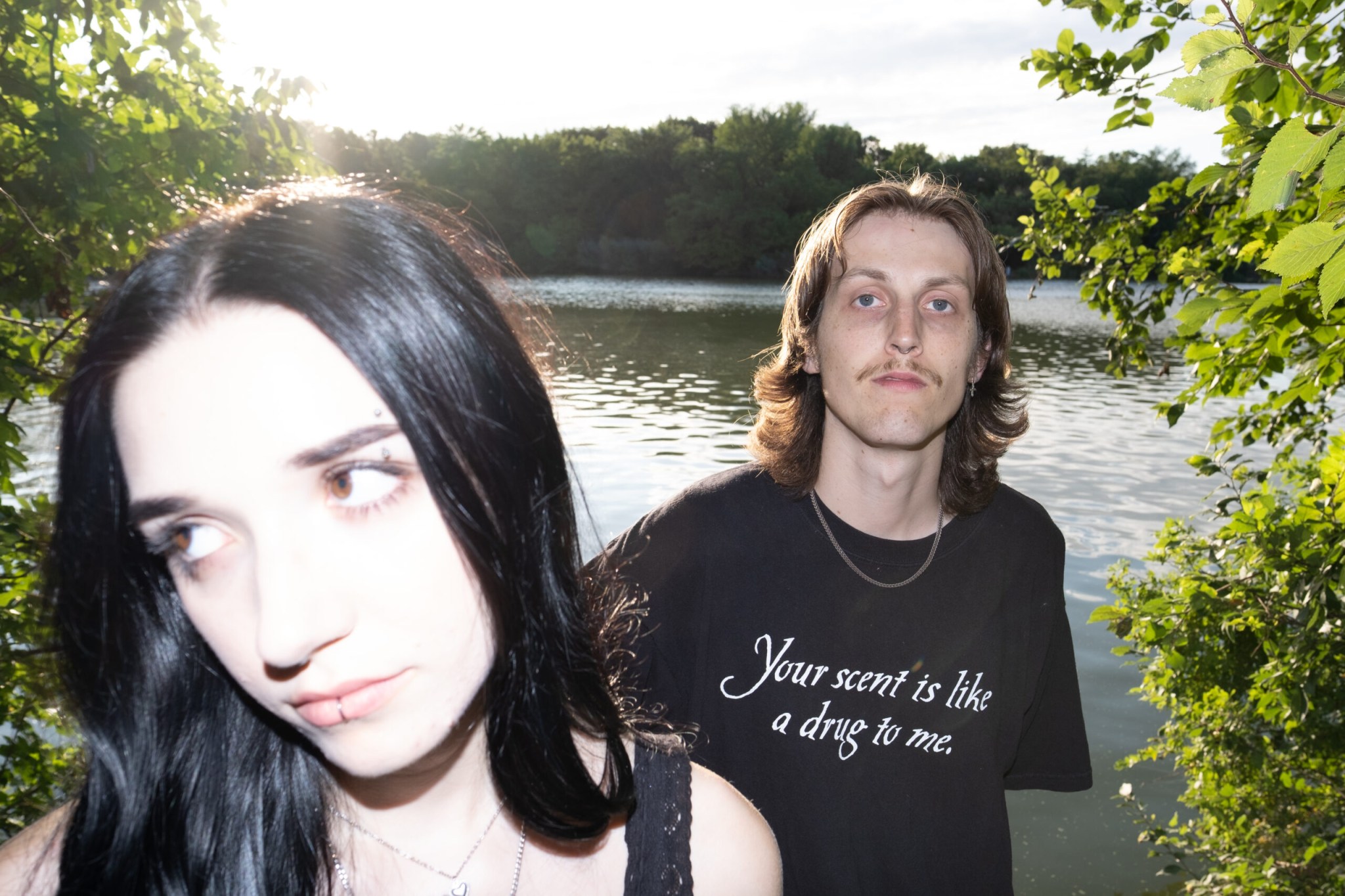 smush members standing close to a lake with trees on the left and right sides of them.