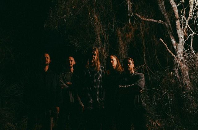 Wage War members standing next to each other in a dark forest.